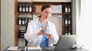 Çekici kadın doktor konuşuyor ve hastaya tıbbi tedaviyi ofisteki bilgisayarla anlatıyor.