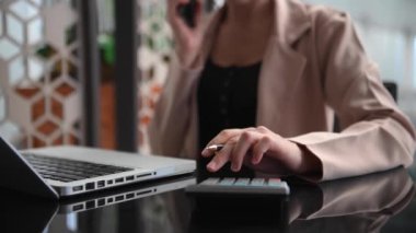 İş kadını, muhasebe konsepti ve hesap makinesi kullanarak masa başında çalışıyor.