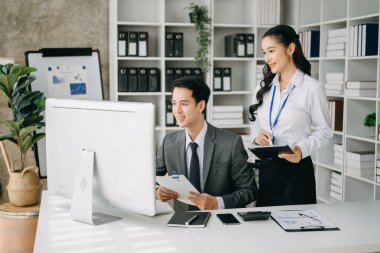 Asyalı iş adamları bilgisayar ve tablet kullanarak sunar ve açıklar. Takım çalışması, finansal pazarlama ekibi, modern ofis odasında otururken.