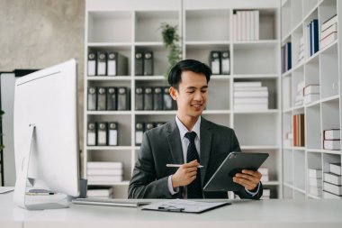 Modern ofis içinde bilgisayar üzerinde çalışan genç işadamı.