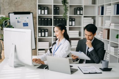 İki Asyalı iş adamı merkez ofiste bilgisayar ve dizüstü bilgisayarla konuşuyor..