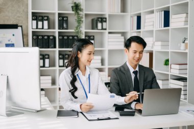 İki Asyalı iş adamı merkez ofiste bilgisayar ve dizüstü bilgisayarla konuşuyor..