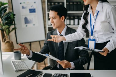 Asyalı iş adamları bilgisayar ve tablet kullanarak sunar ve açıklar. Takım çalışması, finansal pazarlama ekibi, modern ofis odasında otururken.