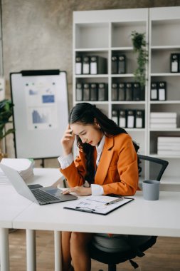 Asyalı kadın migren ağrısı çekiyor. Modern ofiste dizüstü bilgisayar üzerinde çalışırken çok çalışan iş kadını finansörü..
