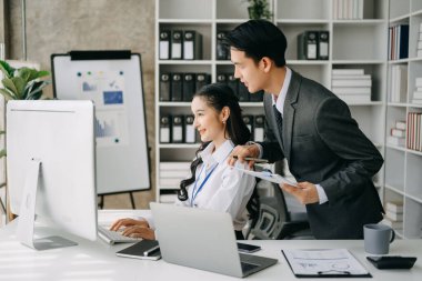 İki Asyalı iş adamı merkez ofiste bilgisayar ve dizüstü bilgisayarla konuşuyor..