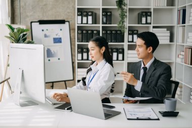 İki Asyalı iş adamı merkez ofiste bilgisayar ve dizüstü bilgisayarla konuşuyor..
