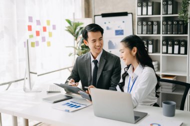 İki Asyalı iş adamı merkez ofiste bilgisayar ve dizüstü bilgisayarla konuşuyor..