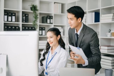 İki Asyalı iş adamı merkez ofiste bilgisayar ve dizüstü bilgisayarla konuşuyor..