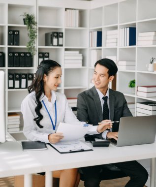 İki Asyalı iş adamı merkez ofiste bilgisayar ve dizüstü bilgisayarla konuşuyor..