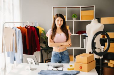 Moda blogcusu konsepti, genç Asyalı kadın video yayınında kıyafet satıyor. Akıllı telefon ve tablet kullanarak küçük işletme KOBİ 'si kurun.