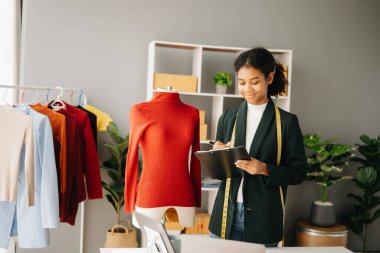 Sakin, kıvırcık esmer, koyu tenli kadın modern moda tasarımcısı ve pano ofisinde masanın üstünde.
