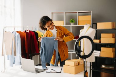 Moda blogcusu konsepti, genç Afrikalı kadın video yayınında kıyafet satıyor. Akıllı telefon ve dizüstü bilgisayar kullanarak küçük işletme KOBİ 'si kurun.