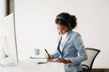 Ciddi çağrı merkezi operatörü, kablosuz kulaklıkla müşteriyle konuşuyor, kulaklıklı Afrikalı kadın, iş merkezindeki müşteri destek servisinde mikrofon danışmanı müşteri arıyor.