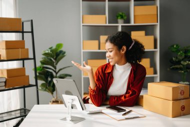 Başlangıçta küçük işletme KOBİ 'si, akıllı telefon ya da tablet kullanan girişimci Afrikalı kadın paket ürün kutusu hazırlamak için online alışveriş siparişini alıp kontrol ediyor. Merkez ofiste.