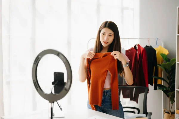 stock image Fashion blogger concept, Young Asian woman selling clothes on video streaming.Startup small business SME, using smartphone  taking receive and checking in office