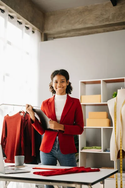 stock image Calm curly brunette, dark skinned woman on desk in modern office of fashion designer and  laptop