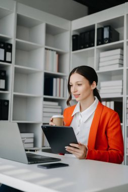 Bir ofis masasında, vergi, rapor, muhasebe, istatistik ve analitik araştırma konseptinde matematik finansmanı yapmak için tablet ve laptop kullanan iş kadını
