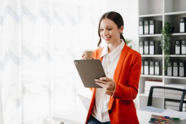 Yaratıcı ofiste dijital tableti ve kahvesi olan kendine güvenen bir iş kadını.