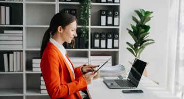 Bir ofis masasında, vergi, rapor, muhasebe, istatistik ve analitik araştırma konseptinde matematik finansmanı yapmak için tablet ve laptop kullanan iş kadını