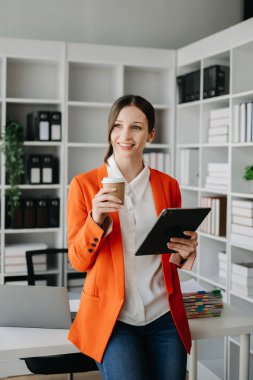 Yaratıcı ofiste dijital tableti ve kahvesi olan kendine güvenen bir iş kadını.