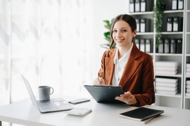 Bir ofis masasında, vergi, rapor, muhasebe, istatistik ve analitik araştırma konseptinde matematik finansmanı yapmak için tablet ve laptop kullanan iş kadını