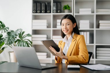 Ofiste tablet ve laptop kullanan Asyalı İş kadını