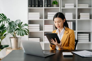 Tablet ve dizüstü bilgisayarla çalışan Asyalı iş kadını 