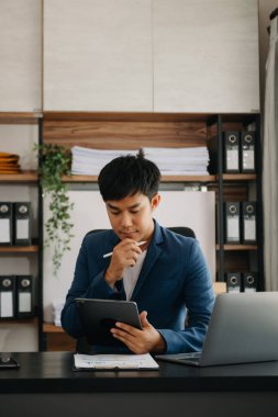 Bilgisayarlı ve tabletli iş adamı yöneticisi online webinar eğitimi izliyor ya da modern ofiste pazar araştırması yaparak sanal toplantı video konferansı yapıyor..