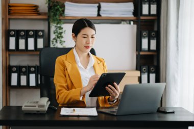 Bir ofis masası, vergi, rapor, muhasebe, istatistik ve analitik araştırma konseptinde matematik finansmanı için tablet ve dizüstü bilgisayar kullanan iş kadını