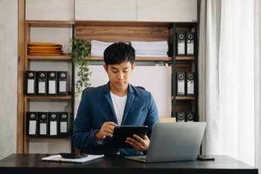 Bilgisayarlı ve tabletli iş adamı yöneticisi online webinar eğitimi izliyor ya da modern ofiste pazar araştırması yaparak sanal toplantı video konferansı yapıyor..