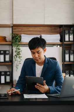 Bilgisayarlı ve tabletli iş adamı yöneticisi online webinar eğitimi izliyor ya da modern ofiste pazar araştırması yaparak sanal toplantı video konferansı yapıyor..