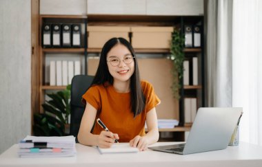  Asyalı kız masada dizüstü bilgisayar kullanarak oturuyor. 