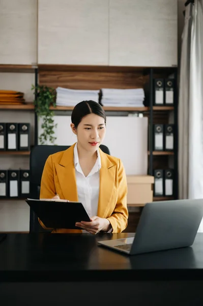 Businesswoman using  laptop for doing math finance on an office desk, tax, report, accounting, statistics, and analytical research concept in modern office