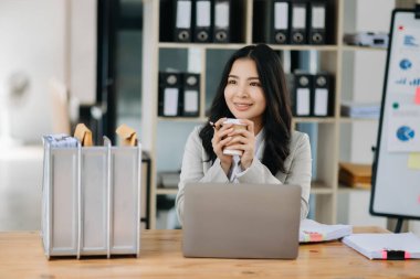 Genç çekici Asyalı kadın ofis çalışanı ofiste gülümsüyor.