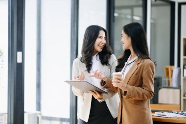 Nazik yönetici yönetici, modern ofisteki Asyalı bayan pazarlama yöneticisiyle iş çözümlerini paylaşır ve tartışır..