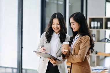 Nazik yönetici yönetici, modern ofisteki Asyalı bayan pazarlama yöneticisiyle iş çözümlerini paylaşır ve tartışır..