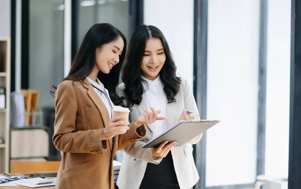 stock image Kind leader executive manager share and discuss business solutions plan ideas on clipboard with Asian female marketing manager in modern office.