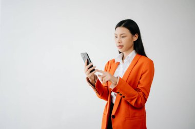 Mutlu hisseden ve beyaz arka planda akıllı telefon tutan güzel Asyalı kadının portre fotoğrafı reklam veya ürün sunumu konsepti için kullanılabilir