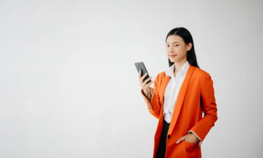 Mutlu hisseden ve beyaz arka planda akıllı telefon tutan güzel Asyalı kadının portre fotoğrafı reklam veya ürün sunumu konsepti için kullanılabilir