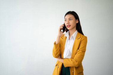 Mutlu hisseden ve beyaz arka planda akıllı telefon tutan güzel Asyalı kadının portre fotoğrafı reklam veya ürün sunumu konsepti için kullanılabilir