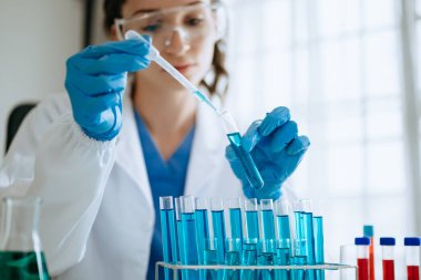 Kadın biyoteknoloji uzmanı bir laboratuarda yeni kimyasal maddeler test ediyor..