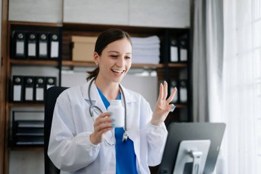 Çekici kadın doktor konuşuyor ve hastaya tıbbi tedaviyi ofisteki bilgisayarla anlatıyor.