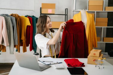 Moda blogcusu konsepti, video yayınında kıyafet satan genç kadın. Ev ofisinde dizüstü bilgisayar kullanarak küçük işletme KOBİ 'si kurun.