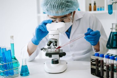 Erkek bilim adamı bir laboratuarda deney yapıyor.