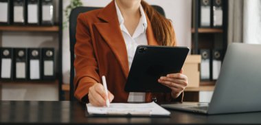 İş kadını ofiste dizüstü bilgisayar ve tablet kullanıyor.
