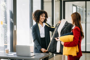 Çeşitli kadın moda tasarımcıları boyunlarında santimetre boyayla iş başında ve not defteri tutuyorlar. bağımsız yaratıcı tasarım işi.