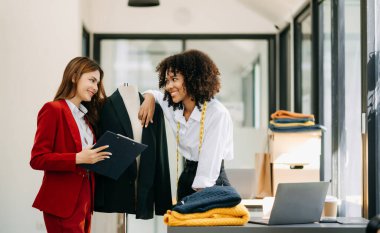 Moda tasarımcılarından birkaçı stüdyo dolusu dizüstü bilgisayarlı terzilik aletleriyle çalışıyor.