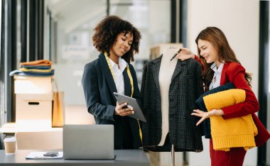 Çeşitli kadın moda tasarımcıları boyunlarında santimetre boyayla iş başında ve tablet tutuyorlar. bağımsız yaratıcı tasarım işi.