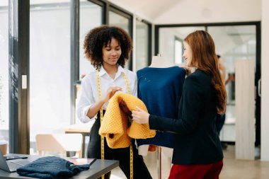 Moda tasarımcılarından birkaçı stüdyo dolusu dizüstü bilgisayarlı terzilik aletleriyle çalışıyor.