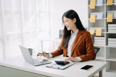 Modern ofiste dizüstü bilgisayarla çalışan Asyalı bir iş kadını.